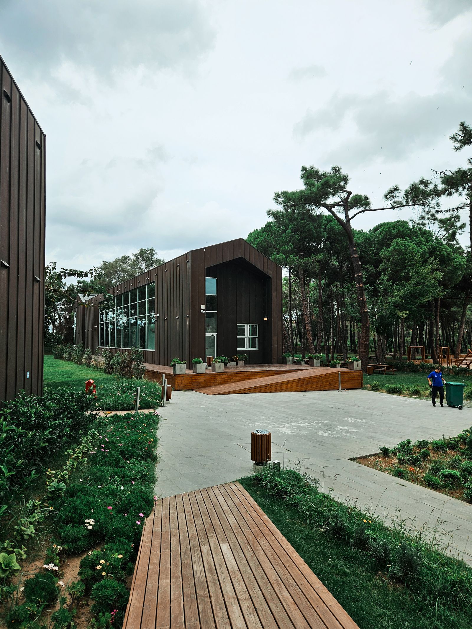Contemporary building among trees, connected by a wooden walkway